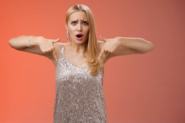 Hayal kırıklığına uğramış, gümüş elbiseli, sarışın, zarif kız arkadaşı kandırmış, suratını buruşturmuş, hoşnutsuz, internetten alınmış ayakkabıları gösterme zahmetine girmiş, kıyafetleri eşleşmiyor, mutsuz duruyor.