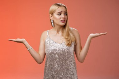 Endişeli, kendine güveni olmayan, tatlı sarışın kız kendini kaybolmuş hissediyor omuz silkiyor, kararları tartıyor, doğru görünüyor.