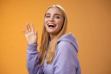 Belden yukarısına dost canlısı, şanslı sarışın el sallayan mutlu bir şekilde gülümseyen kameraman arkadaşınızı selamlayın merhaba deyin.