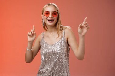 Zarif, kaygısız, harika, sarışın, gümüş elbiseli, kırmızı güneş gözlüklü, neşeli bir şekilde dans eden, dans pistinde dans eden, gülümseyen, eğlenen, eğlenen, eğlenen, vakit geçiren arkadaşlar, stüdyo arkaplanı.