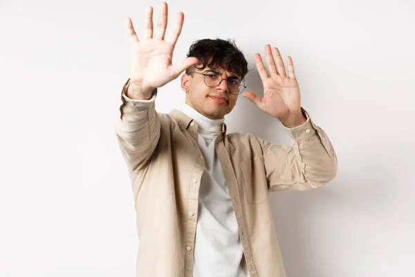 Imagem de homem relutante e irritado levantando as mãos para bloquear a oferta, recusando e pedindo para parar, dizendo não, declinando algo, de pé sobre fundo branco — Fotografia de Stock