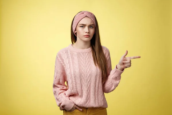 Pissed puzzled young attractive arrogant moody girlfriend in sweater, headband looking irritated, intense frowning pointing finger at copy space, directing person sits on her place, annoyed — Φωτογραφία Αρχείου
