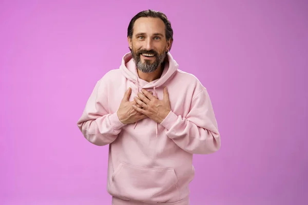 Thankful charming lucky adult bearded man 50s grey hair press palms heart receiving touching heartwarming gesture smiling grateful appreciating effort cherish moment, standing purple background — Stock Photo, Image