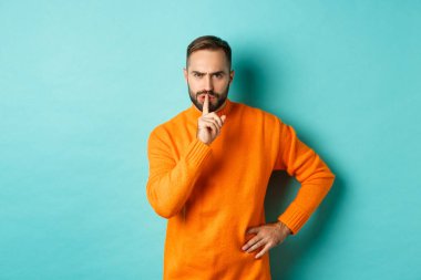 Kızgın sakallı adam sessiz olun diyor, susun ve hoşnutsuz olun, çenenizi kapayın jestlerinizi, turkuaz arka planda durun