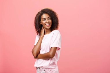 Havadaki aşk gel ve merhaba de. Şehvetli, şehvetli, güzel Afrikalı Amerikalı, afro saçlı, boynuna dokunan genç bir kız öğrenci. Nazikçe sağa dönüyor. Pembe duvarın üzerinde merakla ve arzuyla bakıyor.