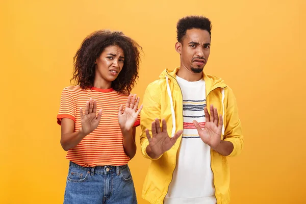 Two african american stylish friends hanging around interrupted by weird guy offering strange proposal shaking hands near chest in refusal and rejection gesture grimacing from aversion and dislike — Stock Photo, Image