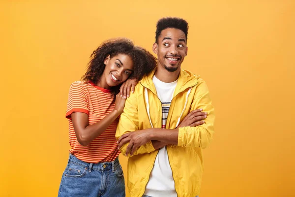 Guy feeling happy girl lean on his shoulder grinning and chuckling from happiness standing pleased and joyful over orange background while woman hugging best friend upbeat she can rely on him — Stock Photo, Image