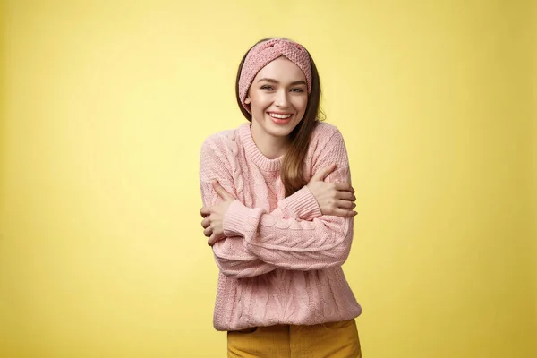 Hace frío, mejor ponte el abrigo. Encantadora joven tierna mujer europea con suéter abrazando brazos cruzados cuerpo sobre el pecho, abrazándose a sí misma para calentar sensación de frío, temblor, sonriendo — Foto de Stock