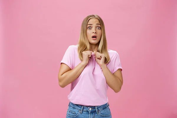 Woman gasping from fright being scared by someone pressing clenched hands to chest bending backwards looking worried and terrified at camera being shocked with unexpected bang over pink wall — Stock Photo, Image