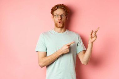 Kızıl sakallı ve saçlı, etkileyici beyaz adam, sağ üst köşeyi işaret ediyor ve hayrete düşüyor, 