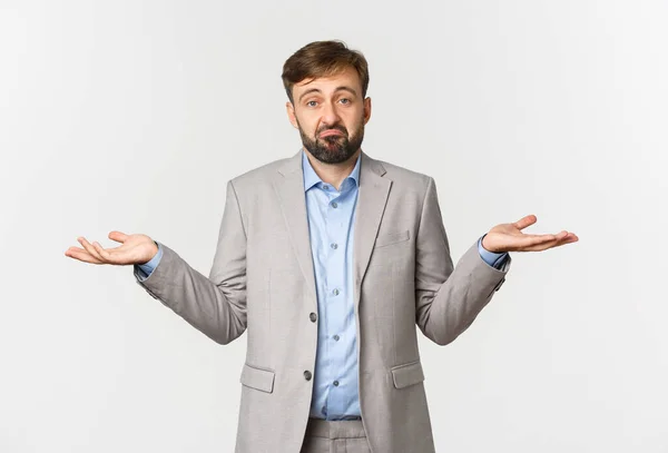 Retrato de hombre de negocios triste en traje gris, encogiéndose de hombros y mirando perplejo, no sé nada, de pie confundido sobre fondo blanco —  Fotos de Stock