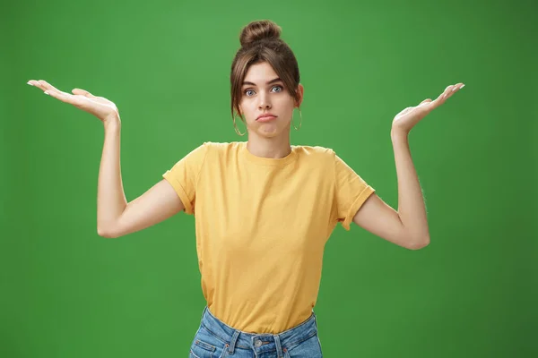 Girl do not know anything. Portrait of confused unsure cute woman with combed hair shrugging with raised hands pouting looking clueless at camera standing questioned against green background — Stock Photo, Image