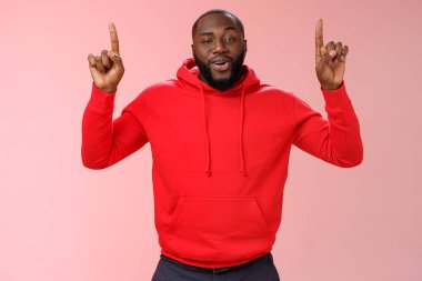 Kibirli, kendini beğenmiş, yakışıklı, afro-amerikan sakallı adam, işaret parmağı kaldırmış, sırıtan, kendine güvenen, harika ürünler öneren, pembe arka plan