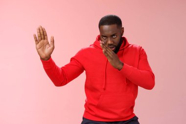 Adam Asyalı dövüş yetenekleri biliyor. Ciddi görünüşlü komik Afro-Amerikalı genç adam dövüş sanatları icra ediyor Kung-fu karate pozisyonu yükseltilmiş avuç içi, pembe arka plan, benimle uğraşmasanız iyi olur.