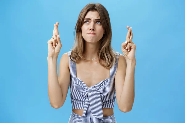 Tour de taille d'une jeune femme pleine d'espoir et inquiète qui attend avec impatience un résultat important en croisant les doigts pour avoir de la chance en tirant les lèvres de la nervosité en regardant fidèlement le coin supérieur gauche — Photo