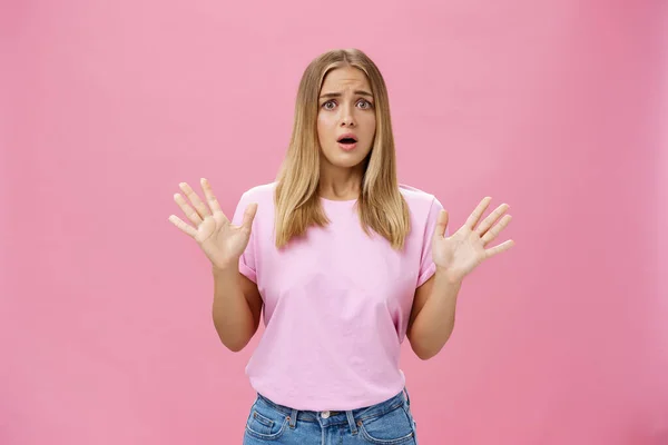 Woman looking nervous explaining with panicking gestures she not involved frowning opening mouth and gasping feeling concerned and worried waving hands over chest posing against pink wall — 图库照片