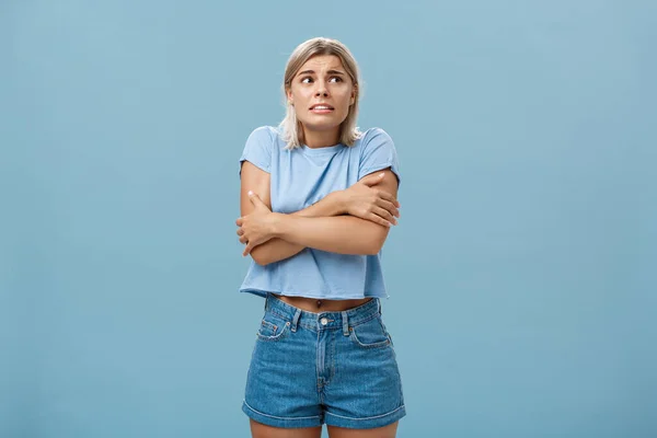 Éteignez le refroidisseur d'air Je suis gelé en été. mécontent mignon caucasien blonde fille dans branché t-shirt étreindre elle-même tout en tremblant de froid secouant regard droit avec inquiet regard sur le mur bleu — Photo