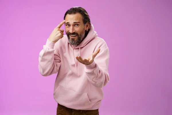 Outraged pissed man angry person crazy out of mind yelling bothered furiously gesturing rolling index finger temple accusing someone insane stupid, standing displeased intense purple background — Stockfoto