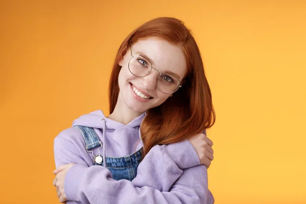 Pasión, ternura, concepto de bienestar. Chica aceptar sí mismo sonriendo encantadora sonrisa inclinación cabeza abrazándose abrazando cuerpo sentir felicidad encantado relajante, mirada coqueta cámara naranja fondo — Foto de Stock