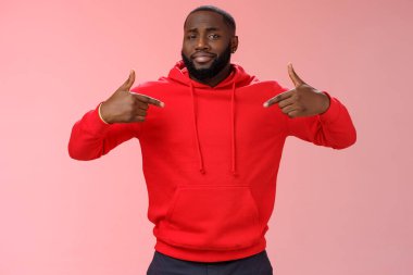 Gururlu, arsız, kendine güvenen, genç, sakallı, afro-amerikan adam kendini göstererek kendini övüyor, ilgi odağı olmak istiyor, zevkle sırıtıyor, pembe arka plan.