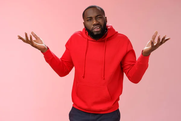 Bothered pissed african american bearded boyfriend in red hoodie arguing standing questioned bothered stupid accusations shrugging raise hands dismay cringing perplexed, pink background — Φωτογραφία Αρχείου