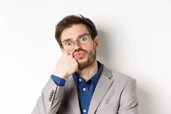 Bored funny office worker in glasses, pouting and holding breath, staring with popped eyes at camera, white background — Stock Photo, Image