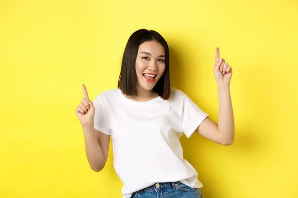 Mujer asiática feliz bailando y divirtiéndose, posando en camiseta blanca sobre fondo amarillo — Foto de Stock