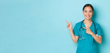 Covid-19, sosyal uzaklık ve koronavirüs salgını konsepti. Profesyonel doktor, kadın hemşire ya da doktor hastaları bilgilendirir. Sol üst köşeyi işaret ederek klinik afişini gösterir.