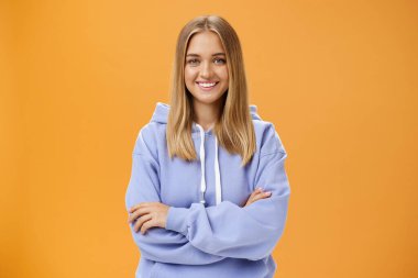 Yaratıcı ve hırslı genç bir kız öğrenci kendi projesini yapıyor serbest çalışıyor, boş zamanı var ve elini göğsüne koyduğunda turuncu kapüşonlu kapüşonlu kapüşon giyiyor.