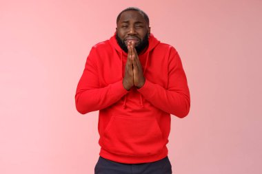 Kırmızı kapüşonlu sefil Afro-Amerikan sakallı adam, yalvaran üzgün, ağlayan, ağlayan, ağlayan, yardım isteyen lütfen el ele tutuşun, merhamet dileyin, özür dileyin, para isteyin.