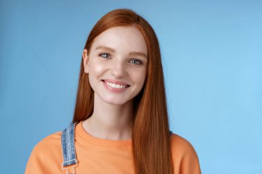 Neşeli, kızıl saçlı, mutlu gülümseyen beyaz kız kameraya bak samimi dostça konuş mükemmel yaz tatilleri geçir arkadaşlarınla konuş neşeli mavi arka planda dur