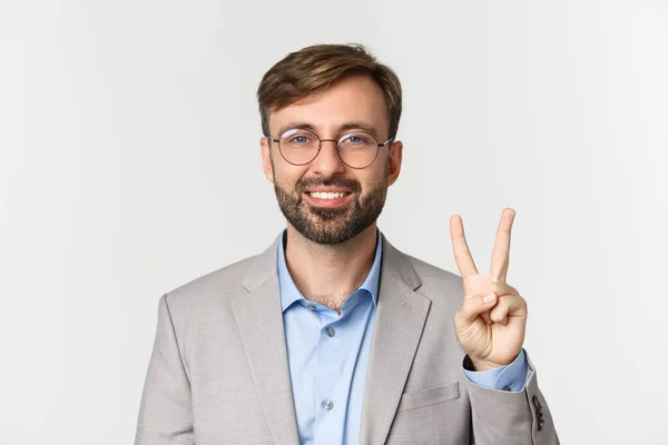 Großaufnahme eines gutaussehenden bärtigen Mannes in Brille und grauem Anzug, der Nummer zwei zeigt und lächelt, vor weißem Hintergrund stehend — Stockfoto
