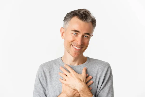 Porträt eines dankbaren Mannes mittleren Alters, die Hände am Herzen haltend und lächelnd, berührt und dankbar, vor weißem Hintergrund stehend — Stockfoto