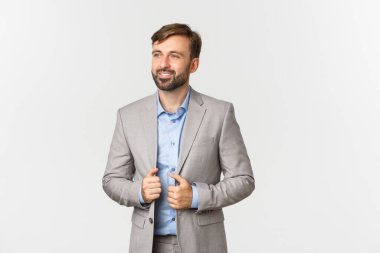 Gri takım elbiseli ve mavi gömlekli başarılı ve kendine güveni tam bir iş adamı görüntüsü.
