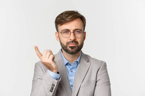 Close-up de empresário pensativo em óculos e terno cinza, agitando o dedo e pensando, fazendo escolha, de pé sobre fundo branco — Fotografia de Stock