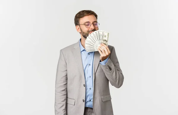 Portret odnoszącego sukcesy szczęśliwego biznesmena, noszącego szary garnitur i okulary, pachnącego pieniędzmi i uśmiechniętego zachwytu, stojącego na białym tle — Zdjęcie stockowe