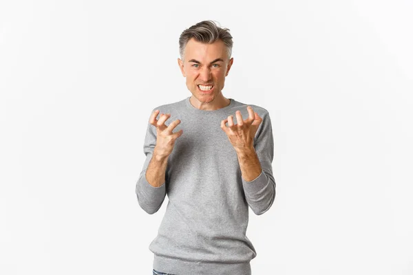 Imagem de homem de meia-idade com raiva amaldiçoando alguém, olhando punhos loucos e apertando com ódio, de pé sobre fundo branco — Fotografia de Stock
