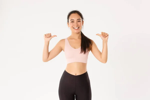 Esporte, bem-estar e conceito de estilo de vida ativo. Orgulhoso e feliz sorrindo asiático feminino instrutor de fitness, esportista apontando para si mesma, ganhando objetivo de treino, tornar-se membro do ginásio, fundo branco — Fotografia de Stock