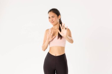 Spor, refah ve aktif yaşam tarzı konsepti. Aktif giyimli, isteksiz ve hoşnutsuz Asyalı bayan sporcu reddedilmiş, suratını buruşturmuş ve iğrenç bir şeye sinmiş, reddedilmiş.