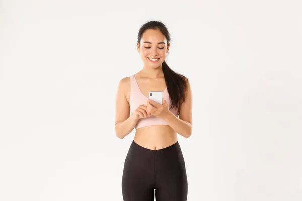 Esporte, tecnologia e conceito de estilo de vida ativo. Sorrindo jovem corredor feminino, esportista saudável usando aplicativo de treinamento de treino, rastreador de água ou aplicativo de esportes no telefone celular, fundo branco — Fotografia de Stock