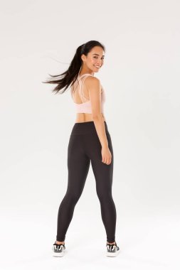 Aktif ve sağlıklı Asyalı fitness kızı, sporcu kadın kameraya tatmin olmuş bir şekilde bakıyor, beden eğitimi koçu antrenmanlara başlıyor, beyaz arka plan.