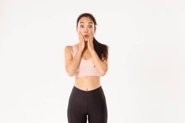 Spor, refah ve aktif yaşam tarzı konsepti. Şaşırmış ve şaşırmış Asyalı tatlı fitness kızı logonuza ya da etkilenmiş yüzünüze bakıyor, mağazadaki özel indirimi duyuyor.