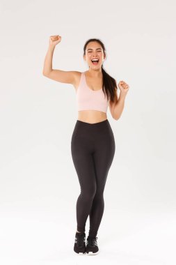 Motivasyonlu ve heyecanlı bayan sporcu, aktif giyimli Asyalı fitness kızı yumruk pompası ve bağırma cesaretlendirme, egzersiz hedefi kazanma, spor salonundaki verimli iyi eğitimle tatmin olma