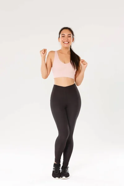 Deporte, gimnasio y concepto corporal saludable. Longitud completa de animada y motivada chica morena asiática listo para el entrenamiento de fitness, bomba de puño y gritos de regocijo, ganar objetivo con la aplicación de entrenamiento — Foto de Stock