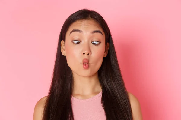 Conceito de beleza, moda e estilo de vida. retrato de engraçado e brincalhão, bobo ásia menina squinting e chupando lábios, fazendo peixe boca como brincando ao redor, pé sobre rosa fundo — Fotografia de Stock