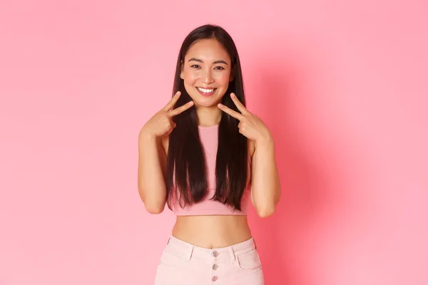 Portrét kawaii usmívající se brunetky dívka v módních letních šatech, ukazující mírové gesta v blízkosti obličeje a hledá pozitivní, propagovat nákupní stránky nebo speciální nabídky na banner, růžové pozadí — Stock fotografie