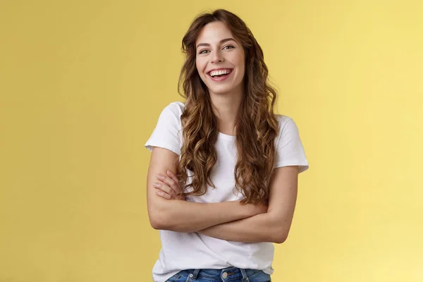 Entretenha-me. Amigável carismático feminino longo corte de cabelo encaracolado rindo alegremente sair amigos cruz braços peito sentir frio ligeiramente frio ter agradável conversa agradável fundo amarelo — Fotografia de Stock