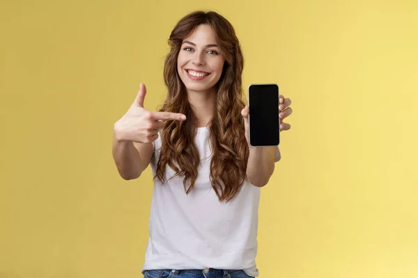 Upbeat säker snygg kvinna visar foto smartphone display hålla mobiltelefon förlängd arm kamera pekar pekfinger mobiltelefon skärm ler glad främja app internet-program — Stockfoto