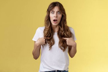 Şok olmuş, sorgulanmış, kıvırcık saçlı kız, soluk soluğa, şaşırmış bakışlar, kendini suçlu hissetmesi, sarsılmış yanlış anlaşılma, sarı arka planda aşağılanmış.