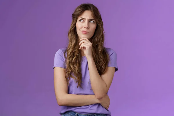 Menina tentando resolver problema pensando solução fazer hmm cara sorrir carrancudo olhar pensativo afastado toque queixo ponderando fazendo escolha decidir como agir o que fazer ficar fundo roxo focado — Fotografia de Stock